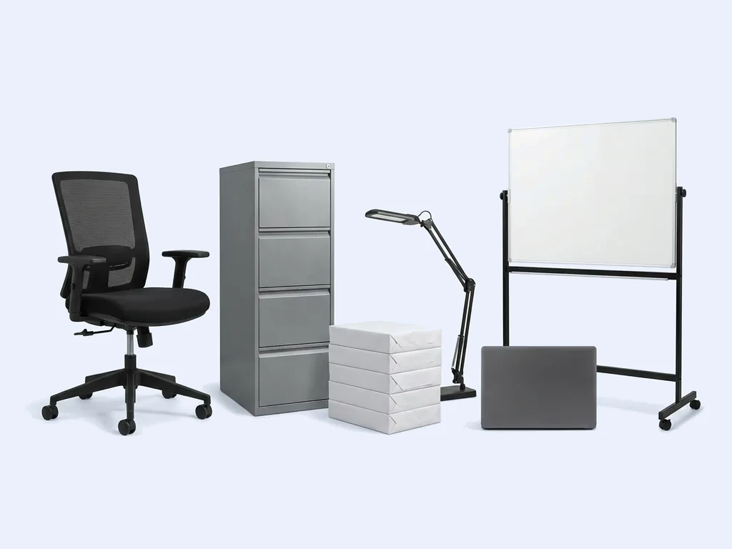 Office chair, filing cabinet, reams of paper, desk lamp, laptop and a mobile whiteboard on a pale studio ground